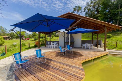 a wooden deck with blue chairs and umbrellas at Villa Estoril in Campina Grande do Sul
