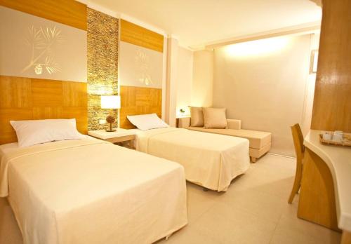 a hotel room with two beds and a chair at Chalet Baguio in Baguio