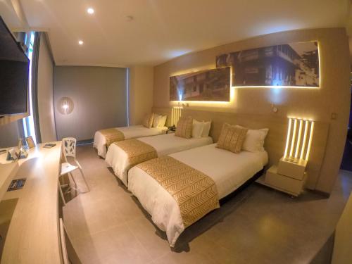 a hotel room with two beds in a room at Hotel Perla Suite Santa Marta in Santa Marta