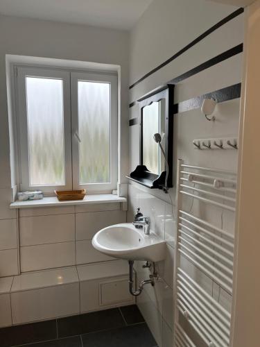 a white bathroom with a sink and two windows at Downtown Apartments in Bremen