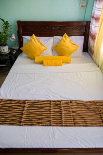- un lit avec des oreillers jaunes et une tête de lit en bois dans l'établissement Sascha's Resort Oslob, à Oslob