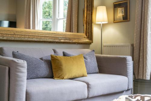 a couch with a yellow pillow in a living room at Victorian Townhouse 5 bedrooms Cheltenham in Cheltenham