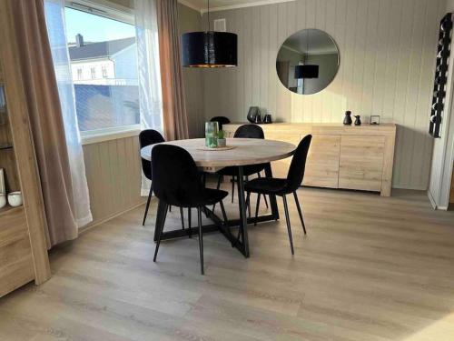 a dining room table with black chairs and a mirror at Solhøgda in Sortland