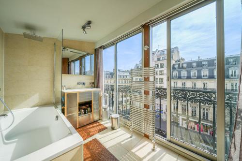 une salle de bain avec baignoire et une grande fenêtre dans l'établissement Appartement Grands Boulevards, à Paris