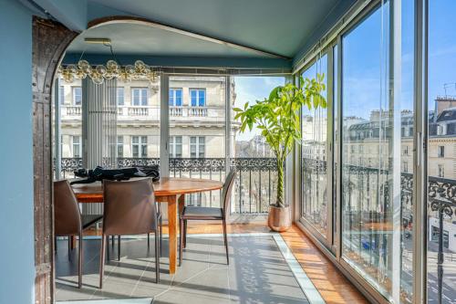 un balcon avec une table et des chaises et une grande fenêtre dans l'établissement Appartement Grands Boulevards, à Paris