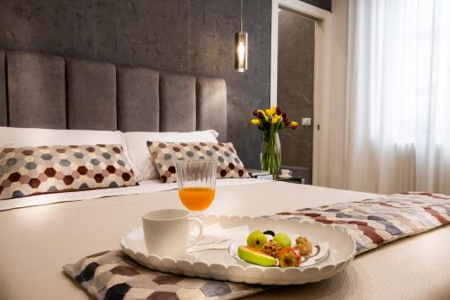 a tray of fruit and a glass of orange juice on a bed at Ducrot Apartment in Palermo
