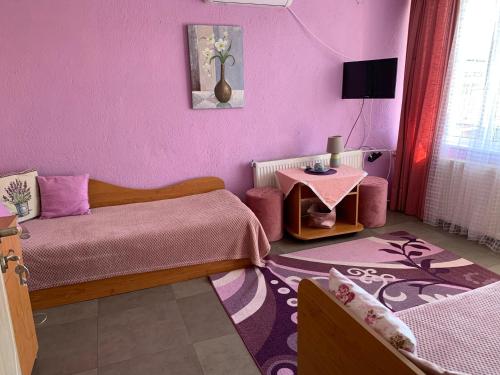 a bedroom with two beds and a pink wall at Къща за гости Стойнови in Pavel Banya