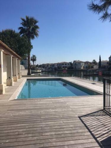 une grande piscine avec une terrasse en bois dans l'établissement Marina 4 adultes 4 enfants piscine commune, à Aigues-Mortes