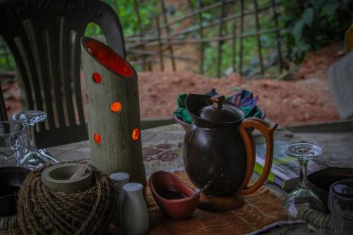 una mesa con una jarra y tazas en una mesa en Tropical river resort en Bulatkohupitiya