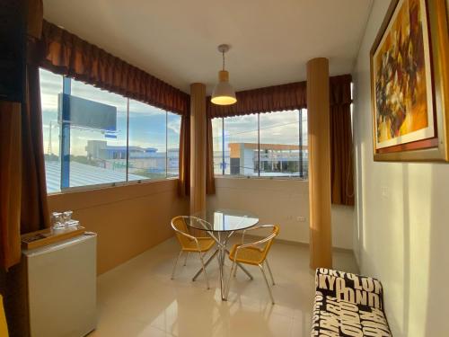 a dining room with a table and chairs and windows at Suite Apart Miraflores in Piura