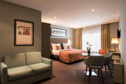 a hotel room with a bed and a couch and a table at Aragon House in Bruges