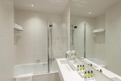 La salle de bains blanche est pourvue d'une baignoire et d'une douche. dans l'établissement Aragon House, à Bruges