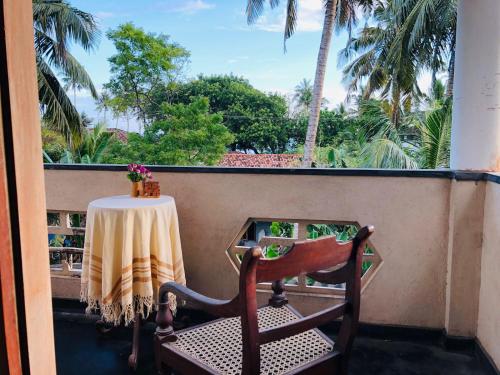 a table and a chair on a balcony with palm trees at Dheera niwasa villa in Talpe