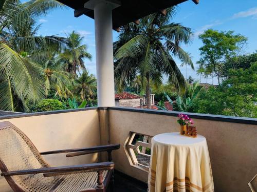 a table and chairs on a balcony with palm trees at Dheera niwasa villa in Talpe