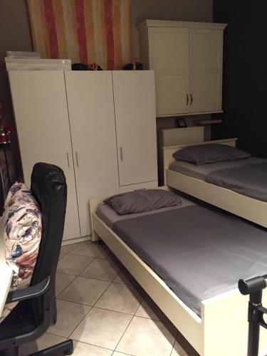 two beds in a room with a chair and cabinets at The A project, Gallery Suites in Agria