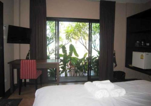 1 dormitorio con cama, escritorio y ventana en Chidlom Resort, en Haad Chao Samran