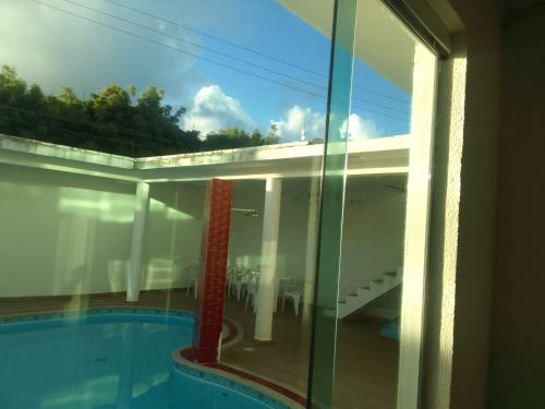 een glazen raam met uitzicht op een zwembad bij Pousada Cantinho da Barra in Barra de São Miguel