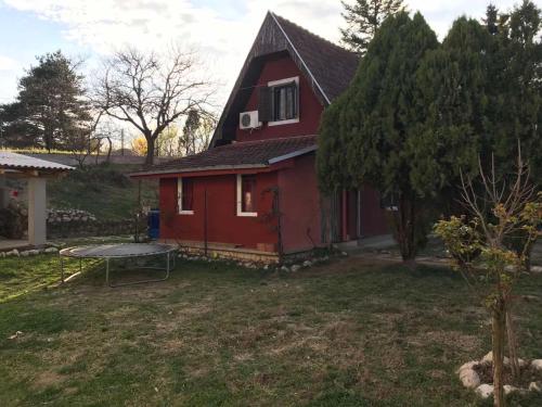 ein rotes Haus mit einem Picknicktisch davor in der Unterkunft Vikendica DUNAV Vinci in Golubac