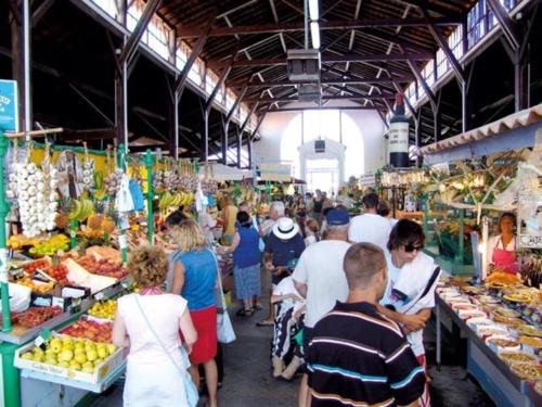 eine Gruppe von Menschen auf einem Markt mit Obst und Gemüse in der Unterkunft Location 1 à 4 pers. dans résidence Front de mer in Soulac-sur-Mer