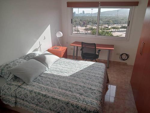 a bedroom with a bed and a desk and a window at Apartamento turístico en Pampatar in Pampatar