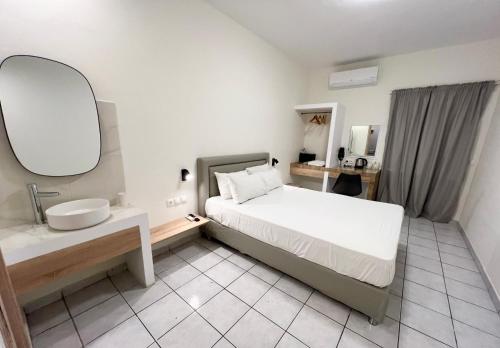 a bedroom with a bed and a sink and a mirror at koukounari 3 superior rooms in Skala