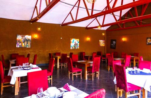 a restaurant with red chairs and tables in a room at Nv Fort Lugard Hotel Iganga in Iganga