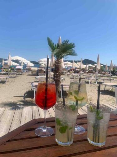 four drinks on a wooden table on a beach at Ferienwohnung Studio Bella Verde in Lesa