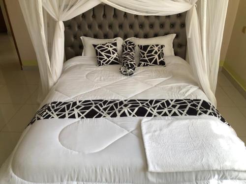 Una cama blanca con almohadas blancas y negras. en VILLA ESPERANZA KITUI en Kitui