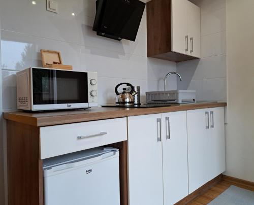 a kitchen with white cabinets and a microwave at Noclegi Pod Modrzewiem in Powidz