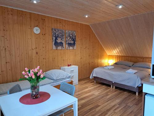 Un dormitorio con 2 camas y una mesa con flores. en Noclegi Pod Modrzewiem en Powidz