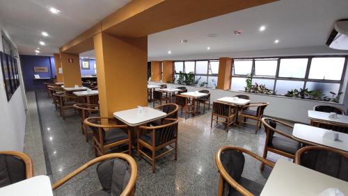 um restaurante com mesas, cadeiras e janelas em César Inn Juiz de Fora Hotel em Juiz de Fora