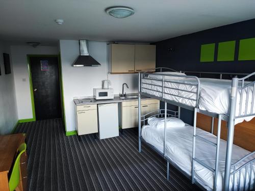 Pokój z 2 łóżkami piętrowymi i kuchnią w obiekcie Happy Guests Lodge w mieście Lower Whitley
