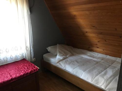 a bedroom with a bed with a wooden wall and a window at Vikendica DUNAV Vinci in Golubac