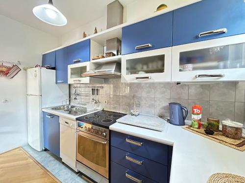 a kitchen with blue cabinets and a refrigerator at Avlija Garden Gem in Sarajevo