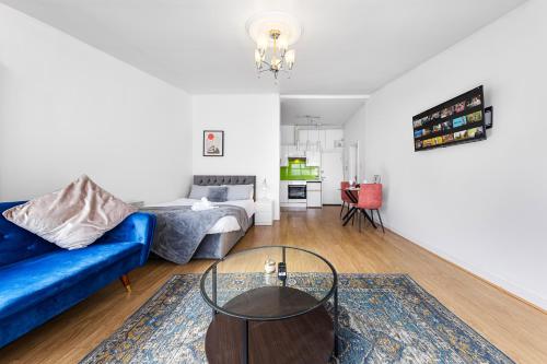 een woonkamer met een blauwe bank en een tafel bij Spacious Studio High Street Location in Londen
