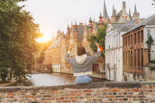 a woman sitting on a wall looking at a city at Aragon House in Bruges