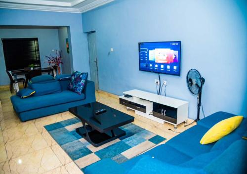 uma sala de estar azul com um sofá azul e uma televisão em Jimms Place em Owerri