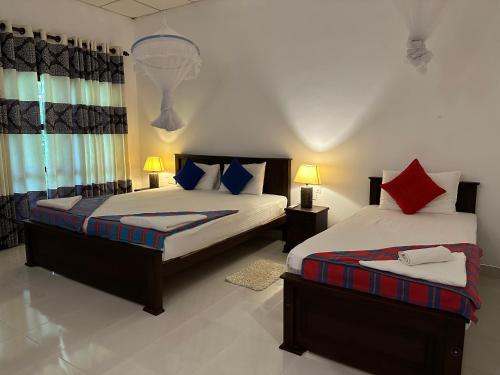 a bedroom with two beds and two lamps at Sigiri Hibiscus Villa in Sigiriya