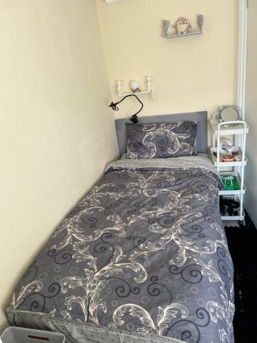 a bedroom with a bed with a gray and white comforter at Quaint and Serene Single room in London