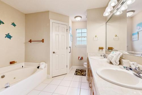 a white bathroom with two sinks and a tub and a tubermott at East Bay Getaway in Navarre