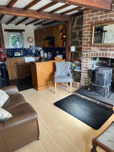 Annie’s Cottage في Llanrhaeadr-ym-Mochnant: مطبخ وغرفة معيشة مع موقد من الطوب