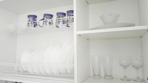 a white cupboard with wine glasses in it at 12 Microragion Apartments in Aktobe