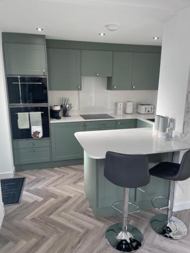 a kitchen with green cabinets and a table and chairs at Savannah Lodge in Weymouth