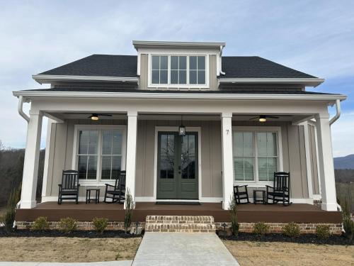 a white house with chairs on the front porch at Kaya Cottages in Dahlonega