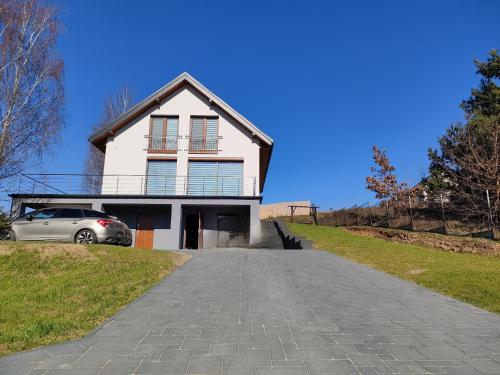 una casa blanca con un coche aparcado en la entrada en Oaza U Leszka-dom całoroczny z sauną i ruską banią, en Podgórze