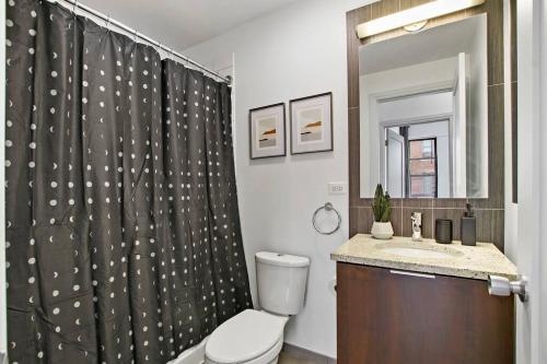 y baño con aseo y cortina de ducha. en 2BR Comfy and Roomy Apt in Chicago - Del Prado 1013 en Chicago
