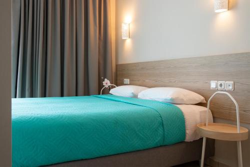 a bedroom with a bed with a blue blanket and a table at Zefyros Sea View Hotel in Platamonas