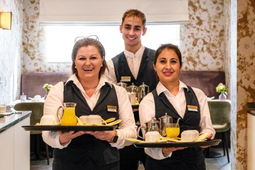 a man and two women holding plates of food at Aragon House in Bruges