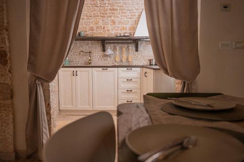 a kitchen with a table and chairs with curtains at B&B TRULLI MIRIVA' in Alberobello