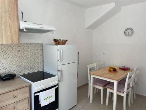 eine Küche mit einem weißen Kühlschrank und einem Tisch in der Unterkunft Casa Di Rosse in Symi